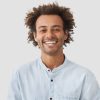 Happy mixed race male student with Afro hairdo shows white teeth, being in good mood after classes as going to have date with female groupmate, stands against white background. Positiveness concept